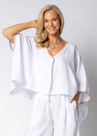 The Mireya Linen Top in White. Relaxed, button-up linen blouse with raw-stitched neckline, styled for warm-weather versatility.