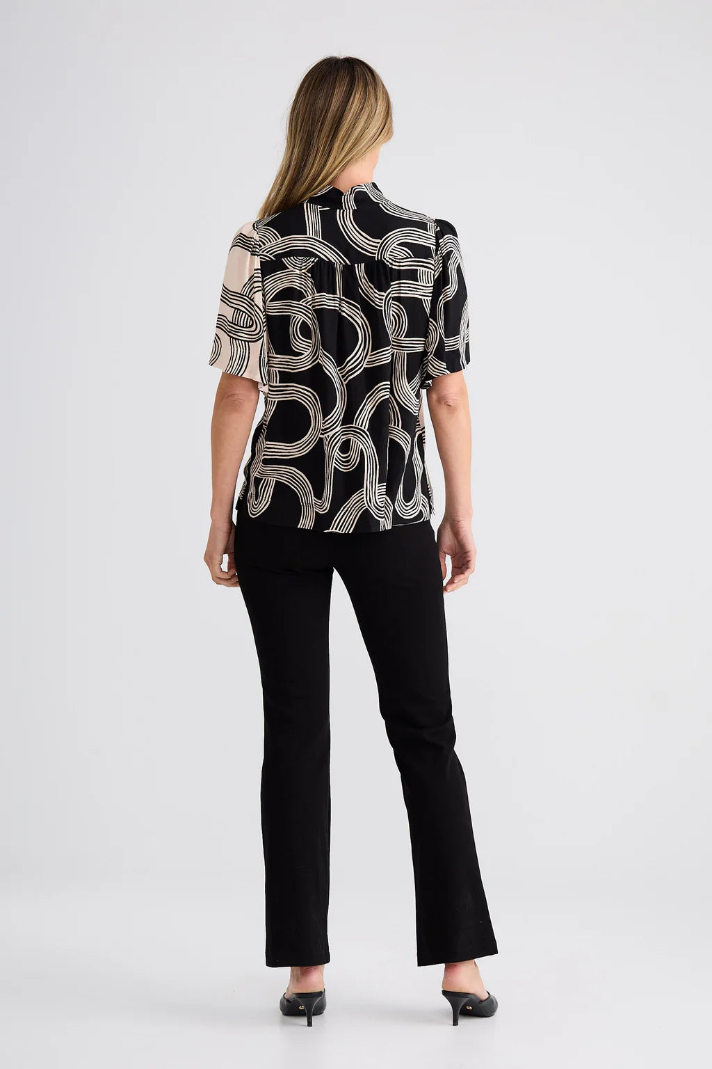 Penelope Top featuring a high-neck collar, self-covered button front with rouleau loops, flared short sleeves, and a relaxed, gathered silhouette with side splits.