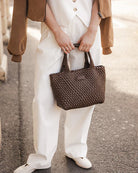 A stylish woven tote bag with top handles and an adjustable crossbody strap, perfect for effortless everyday elegance and versatility.