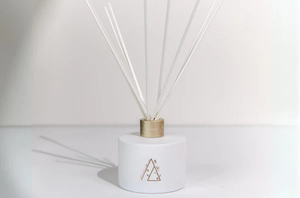 Meeraboo scented reed diffuser in a matte white vessel with gold detailing and natural reeds, designed to provide long-lasting home fragrance.