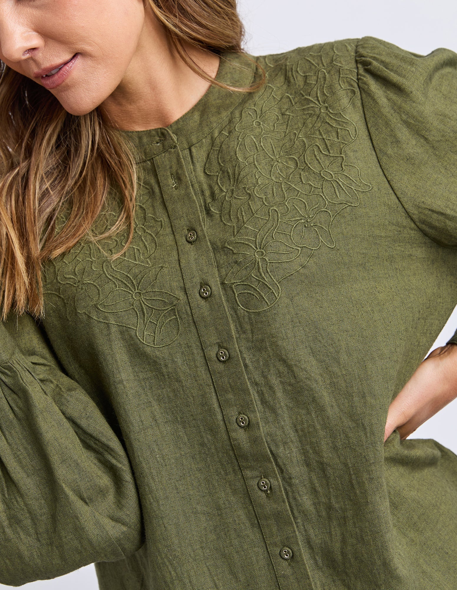 The Eleanor Shirt featuring a high neckline, button-through front, delicate chest embroidery, and softly gathered long sleeves in a relaxed, feminine silhouette.