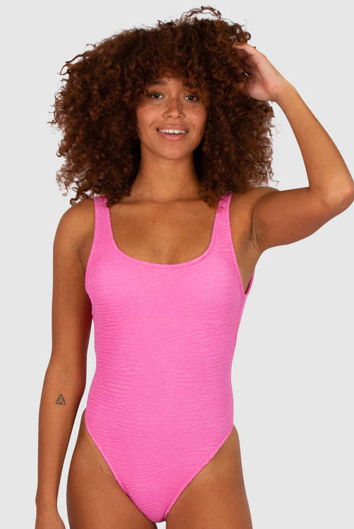 A bold flamingo-pink one-piece swimsuit with a low back, elongated leg line, Rio bottom coverage, and textured Italian fabric for a stylish, flattering fit.