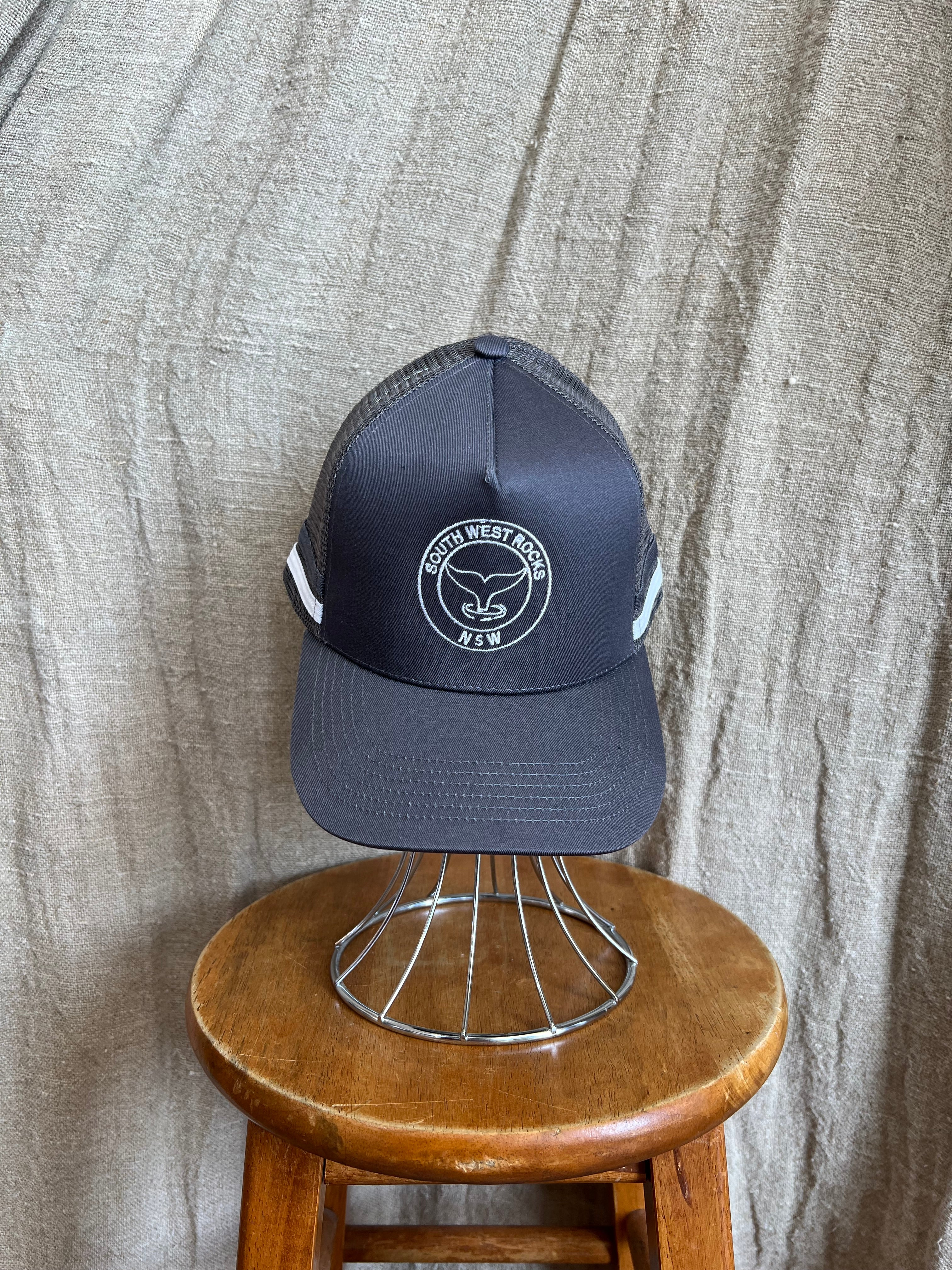 Rocks Hat in black featuring a whale tail design on the front, snapback closure, and breathable mesh sides for a comfortable, adjustable fit.