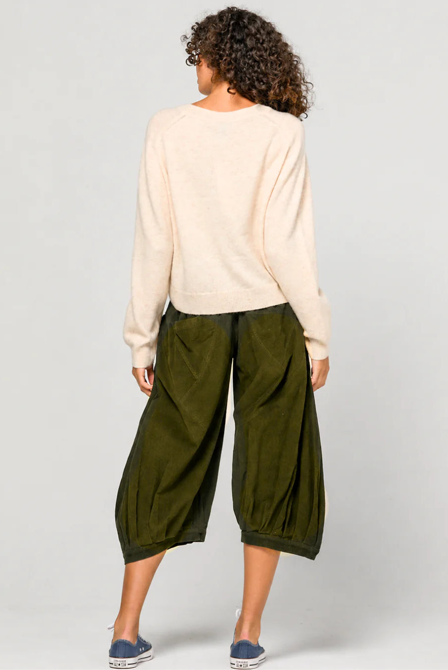 Woman wearing the Cord Guru Pant in Olive Green, featuring a relaxed 3/4 balloon-leg fit in soft cotton cord with a cool-toned khaki finish.