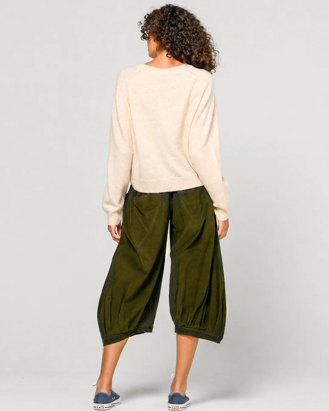 Woman wearing the Cord Guru Pant in Olive Green, featuring a relaxed 3/4 balloon-leg fit in soft cotton cord with a cool-toned khaki finish.