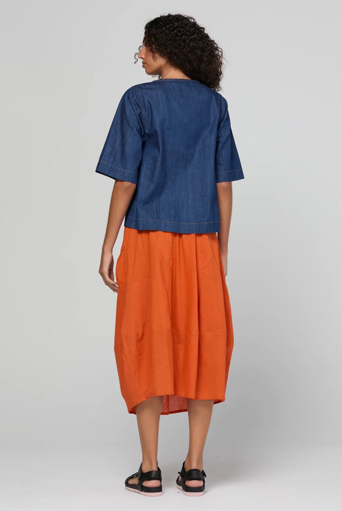 Guru Skirt in Rust, featuring a 3/4 length, stretch drawstring waistband, front and back pockets, full lining and black contrast stitching.