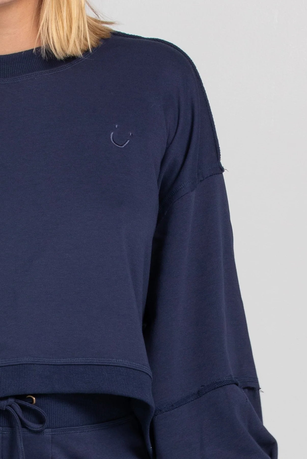 Oversized cropped Guru Sweater with balloon sleeves, contrast stitching, raw seam details, and ribbed neckline, cuffs, and hem with SMILE logo