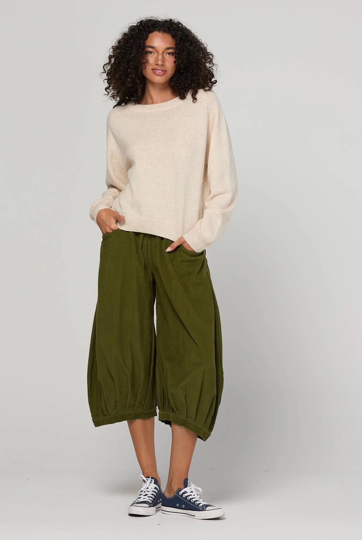 Woman wearing the Cord Guru Pant in Olive Green, featuring a relaxed 3/4 balloon-leg fit in soft cotton cord with a cool-toned khaki finish.