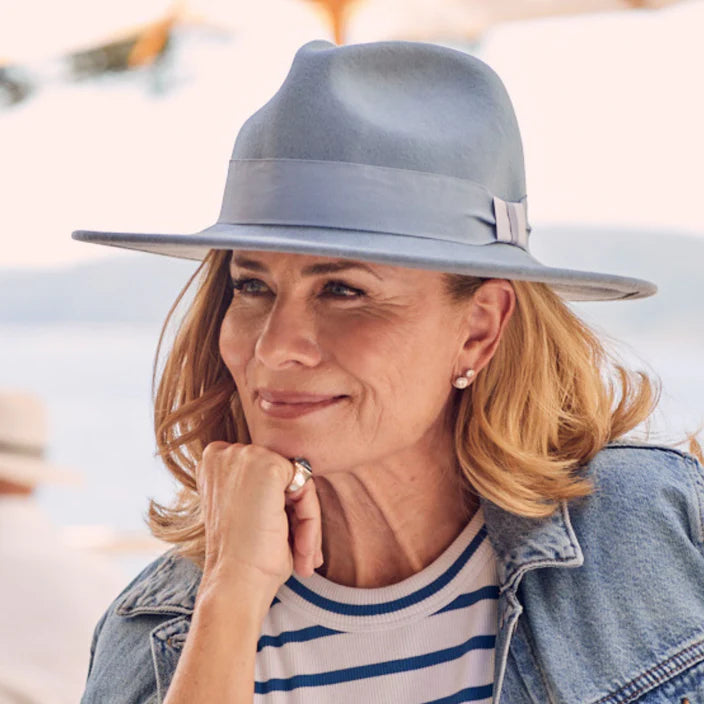 A stylish light blue wool felt fedora with a pinched crown, wide flat brim, and a tonal grosgrain ribbon, offering UPF50+ sun protection and an adjustable ComfyFit band for a perfect fit.