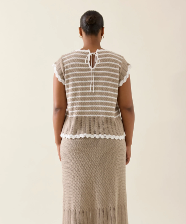 A lightweight, 100% cotton knit top in a soft canvas color, featuring a delicate pointelle texture with subtle horizontal stripes. The top has a relaxed silhouette with scalloped edges along the neckline, sleeves, and hem. A keyhole opening with a tie closure accents the back, adding a refined, feminine detail