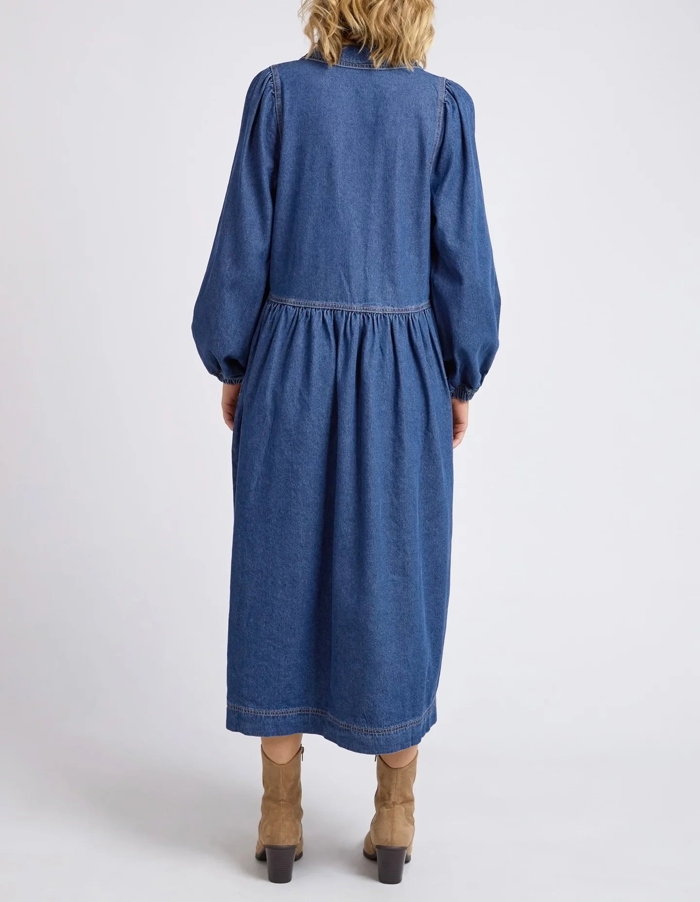 Dark blue wash Josephine Denim Dress by Elm with a V-neck, small collar, gathered waist, puffed long sleeves, and side pockets, crafted from 100% cotton.