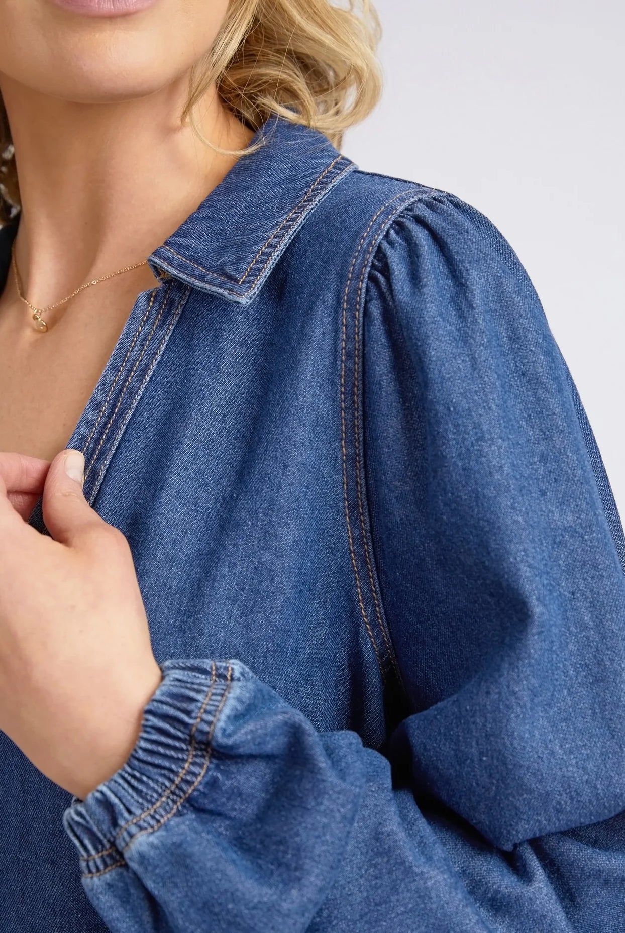 Dark blue wash Josephine Denim Dress by Elm with a V-neck, small collar, gathered waist, puffed long sleeves, and side pockets, crafted from 100% cotton.