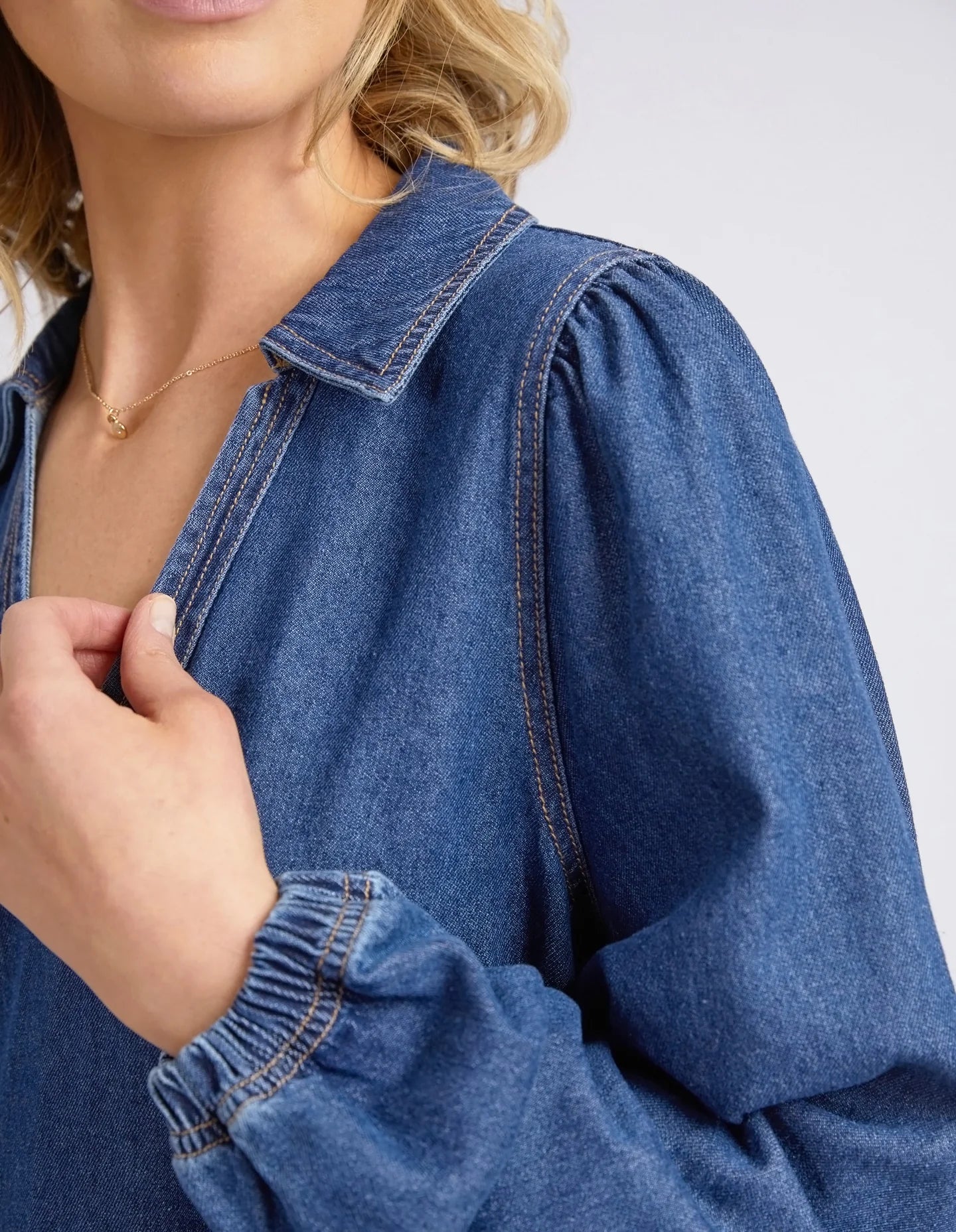 Dark blue wash Josephine Denim Dress by Elm with a V-neck, small collar, gathered waist, puffed long sleeves, and side pockets, crafted from 100% cotton.