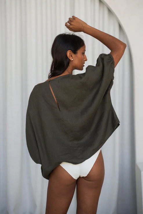 A khaki Tina Linen Top crafted from 100% organic linen. This top showcases a relaxed silhouette with gown-like sleeves finished with elastic cuffs for added sophistication. It includes a back neck opening secured with a shell button, offering a stylish and versatile option for both casual and dressy settings.