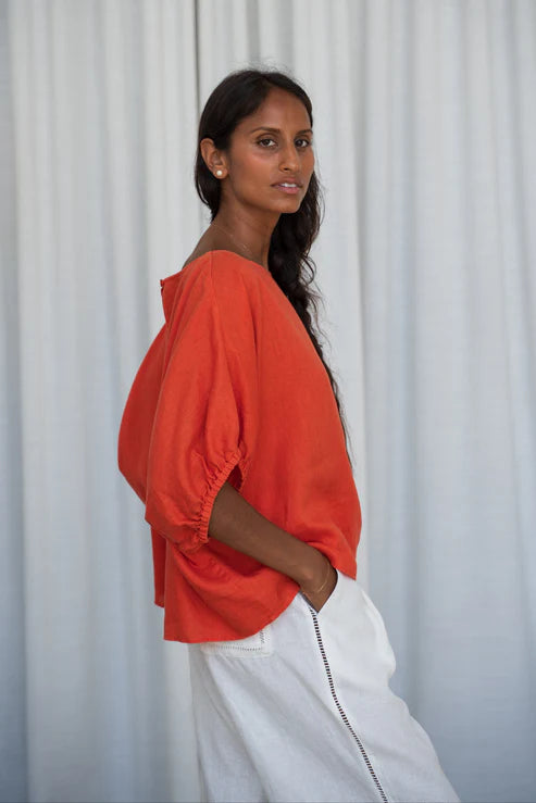 The Lily Pilly Tina Top in vibrant orange spritz is designed with a relaxed silhouette, lightweight feel, and natural linen textured weave.