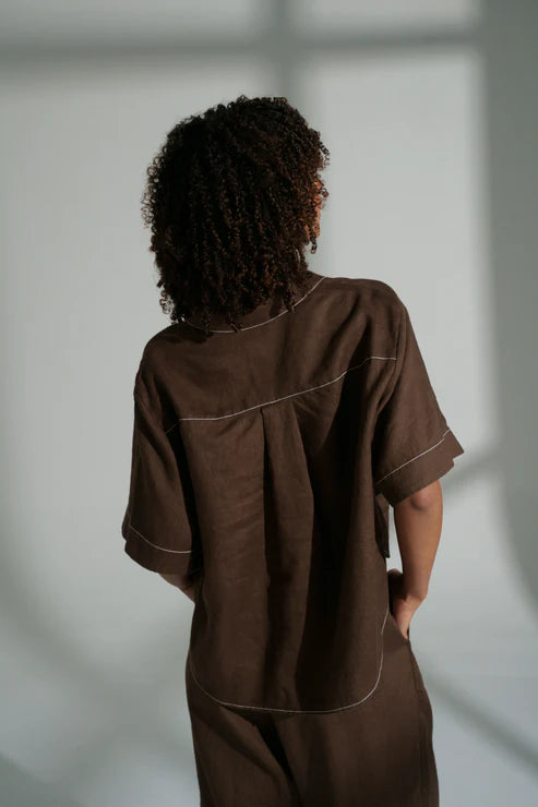 Nika linen shirt in chocolate with relaxed short sleeves, contrast stitching, front pocket, high-low curved hem and corozo buttons.