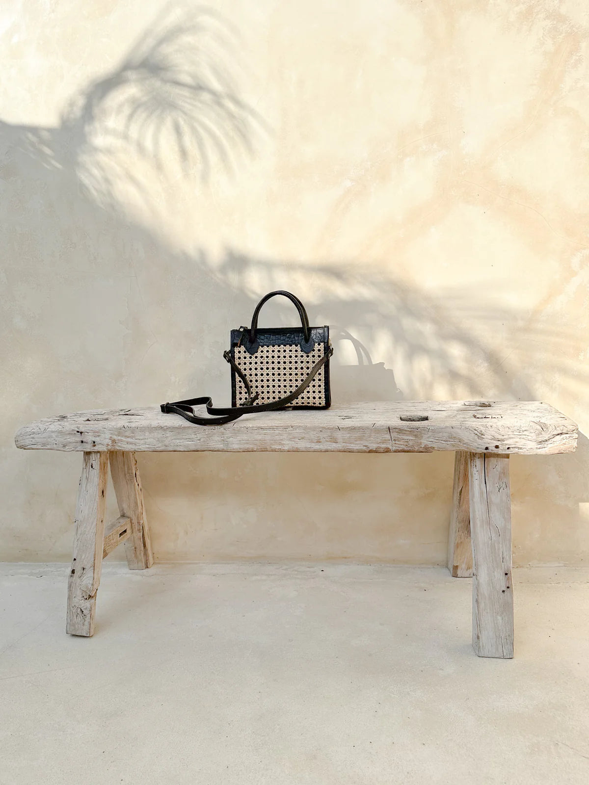 Prague Clutch in black and tan featuring natural rattan weaving with genuine leather accents in a sleek summer-ready design.