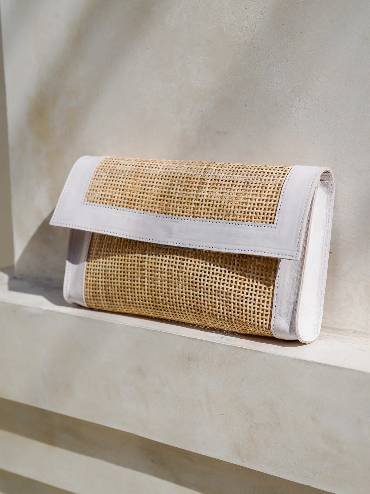 Seoul Clutch in white featuring Indonesian rattan cane webbing with leather trim in a sleek, elegant clutch silhouette.