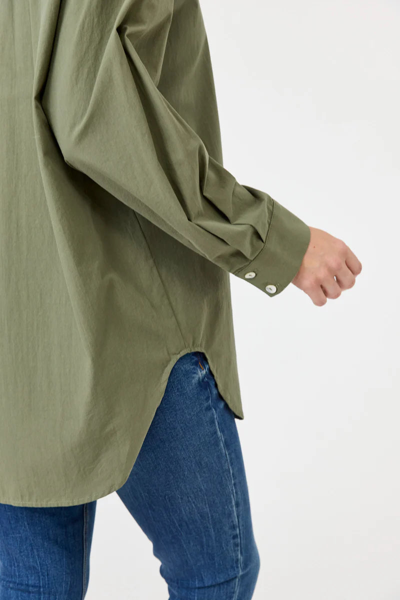 A khaki oversized button-down shirt made from soft cotton, featuring a relaxed fit, classic collar, and long sleeves, styled effortlessly for a casual yet polished look.
