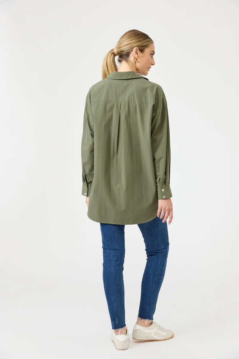 A khaki oversized button-down shirt made from soft cotton, featuring a relaxed fit, classic collar, and long sleeves, styled effortlessly for a casual yet polished look.