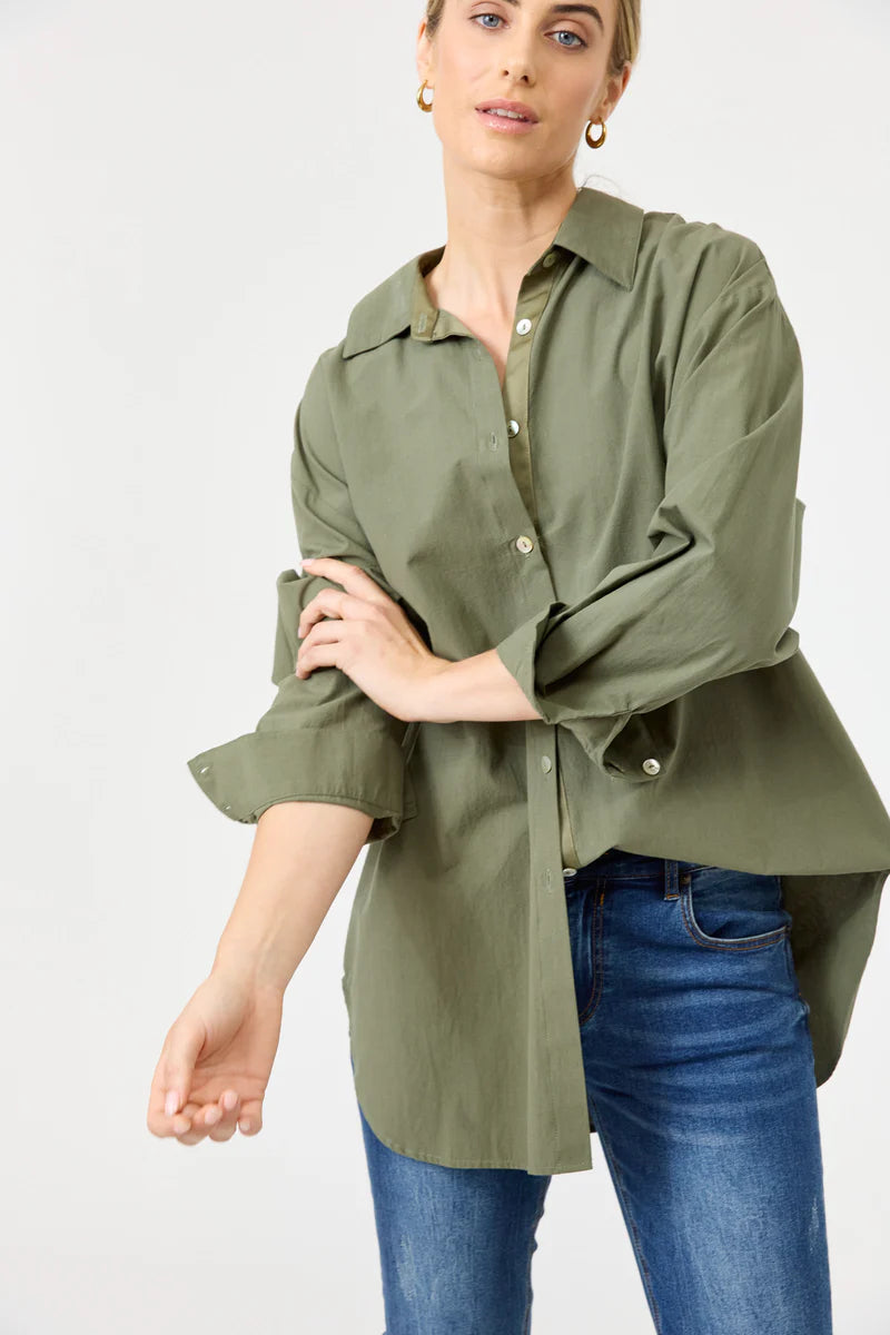 A khaki oversized button-down shirt made from soft cotton, featuring a relaxed fit, classic collar, and long sleeves, styled effortlessly for a casual yet polished look.