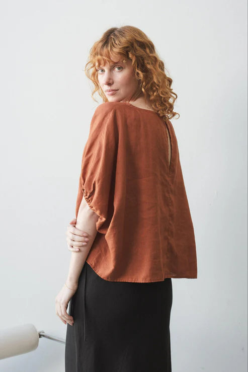 Tina Linen Top in Cajun – A breathable, lightweight linen top in a warm, earthy Cajun hue. Designed with a relaxed fit, short sleeves, and a button-down front for effortless, everyday styling.
