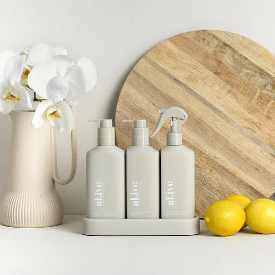 The Alive Kitchen Trio Set, featuring Dishwashing Liquid and Bench Spray in Lemon & Pomegranate scent, and Hand Wash in Watermelon & Lime scent, all neatly arranged in a sleek, custom tray. The white bottles with vibrant, fresh-colored labels are displayed on a clean countertop, exuding a refreshing and vibrant aesthetic with fruity, citrus-inspired fragrances.