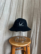 Black bucket hat with a smiley face design.
