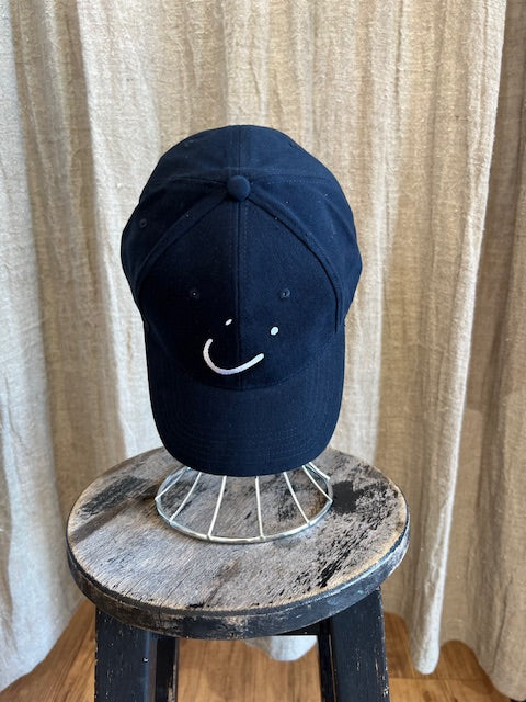 Smiley Cap in Navy with curved brim, adjustable back strap, and embroidered smiley face detail on the front.