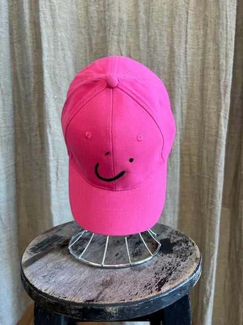 Smiley Cap in Pink with curved brim, adjustable back strap, and embroidered smiley face detail on the front.