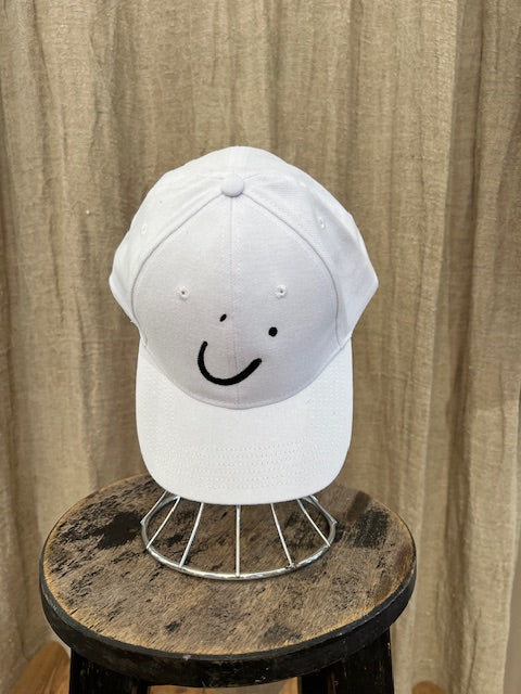 Smiley Cap in White with curved brim, adjustable back strap, and embroidered smiley face detail on the front.