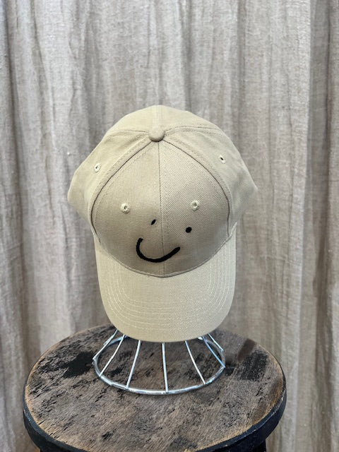 Smiley Cap in Beige with curved brim, adjustable back strap, and embroidered smiley face detail on the front.