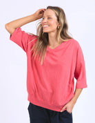 The Mazie Vee Neck in Watermelon Crush, a vibrant relaxed-fit cotton top, features a flattering V-neckline, 3/4 length sleeves, two front pockets, and a lightweight oversized design, ideal for layering or casual wear.