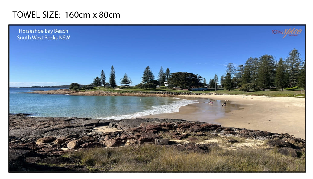 Beach towel featuring a photographic image of Horseshoe Bay, South West Rocks, with location text in the top corner and RawSpice logo in the bottom corner.
