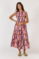 A feminine midi dress in a soft textured Tulip print, made from a cotton-nylon blend. The design features a round neckline with a delicate frill, sleeveless armholes with matching frill trim, and a shirred bodice that contours the figure. A flowing A-line skirt falls to mid-calf, complemented by functional pockets for added ease. The dress offers a relaxed, elegant fit suitable for a variety of occasions