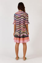 A knee-length dress made from a textured check-weave cotton-nylon blend, featuring a V-neckline with an adjustable tie that can create a rounded neckline. The design includes soft short puff sleeves, a relaxed drop waist, and an easy, feminine silhouette. Lightweight and comfortable, the dress offers a stylish, versatile look suitable for day or night