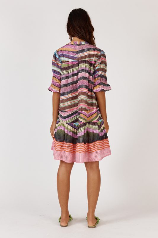 A knee-length dress made from a textured check-weave cotton-nylon blend, featuring a V-neckline with an adjustable tie that can create a rounded neckline. The design includes soft short puff sleeves, a relaxed drop waist, and an easy, feminine silhouette. Lightweight and comfortable, the dress offers a stylish, versatile look suitable for day or night