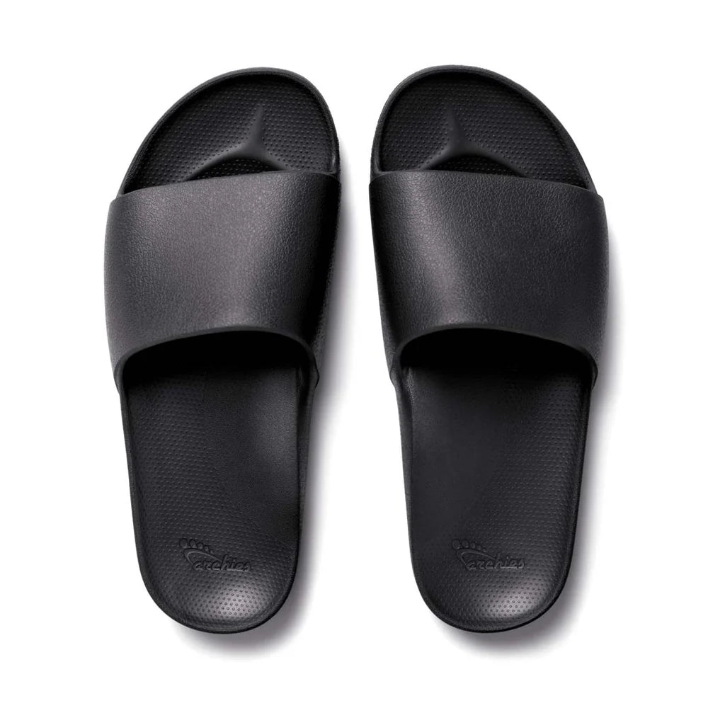 A pair of black arch support slides with a contoured footbed designed for comfort. The slides feature a sleek, minimalist design with a wide strap over the top and a cushioned sole for extra support.