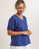 Lightweight denim-colored linen swing top with V-neck and relaxed fit, draping loosely over the body.