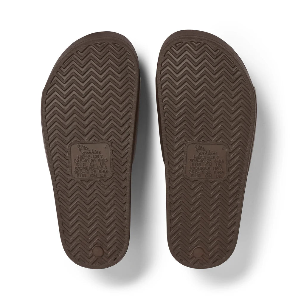 A pair of chocolate brown arch support slides with contoured footbeds and wide straps, designed for comfort and all-day wear.