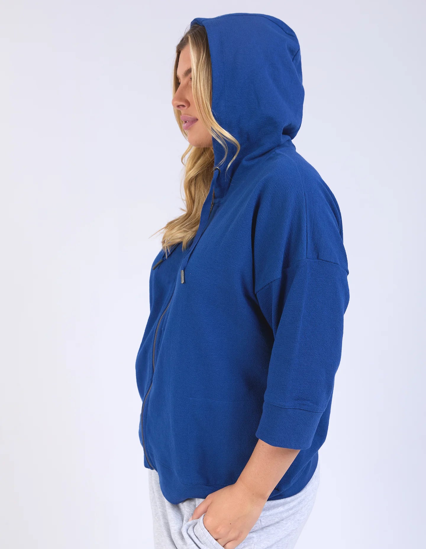 Blue waffle-textured zip-up hoodie with 3/4 length sleeves, a relaxed drop-shoulder fit, and a slightly cropped body for a casual, stylish look.