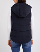 Cord Puffer Vest in Dark Sapphire made from pinwhale cord, featuring a padded design and hood for added warmth.