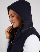 Cord Puffer Vest in Dark Sapphire made from pinwhale cord, featuring a padded design and hood for added warmth.