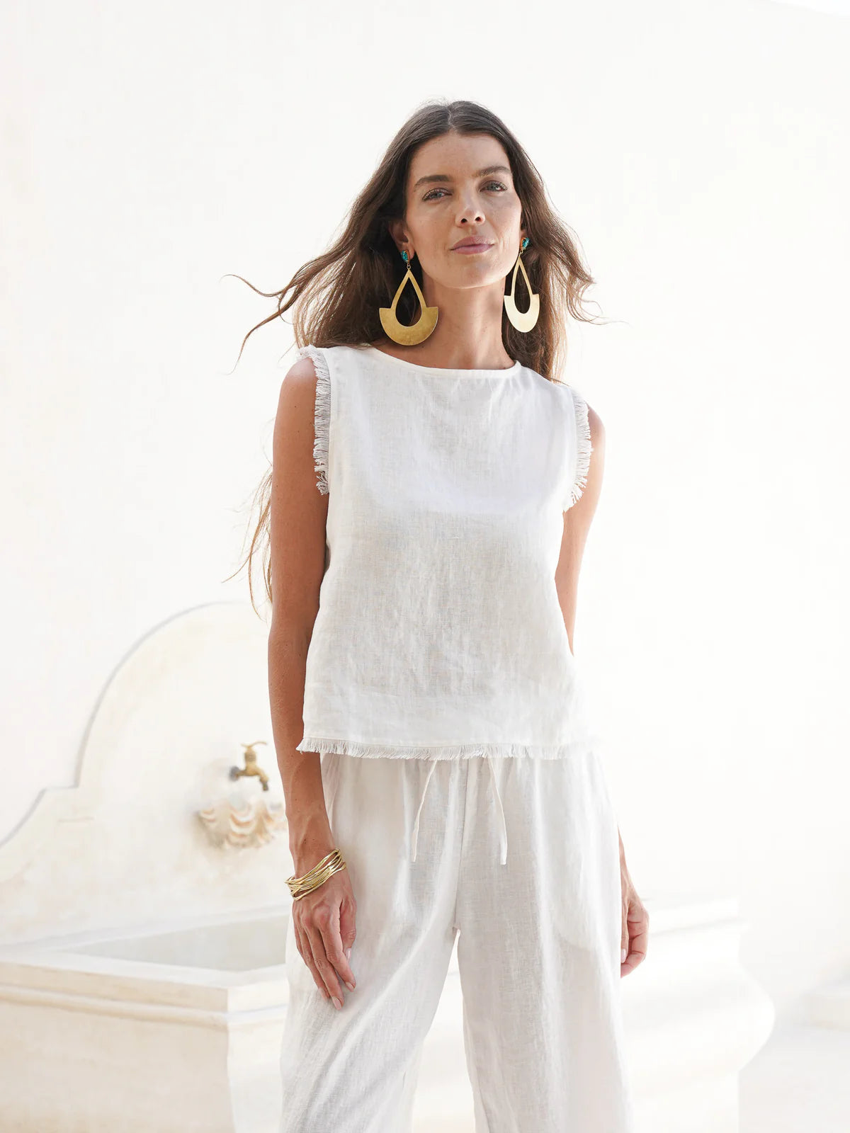 Coconut French linen coastal top with a relaxed fit, soft frayed edges, and button opening at the back, styled for easy summer wear.