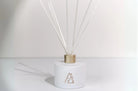 Meeraboo scented reed diffuser in a matte white vessel with gold detailing and natural reeds, designed to provide long-lasting home fragrance.
