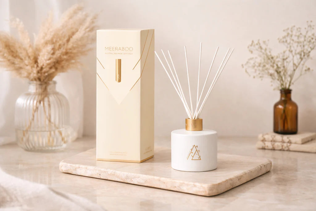Meeraboo scented reed diffuser in a matte white vessel with gold detailing and natural reeds, designed to provide long-lasting home fragrance.
