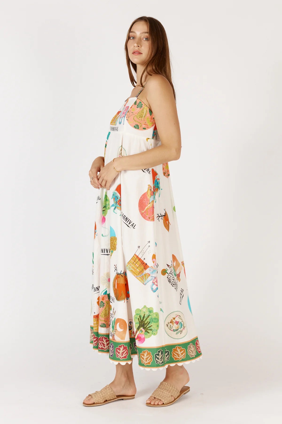 Down Under Sundress in white featuring a colorful carnival print, straight neckline, adjustable straps, and scalloped hem with leaf border detailing.
