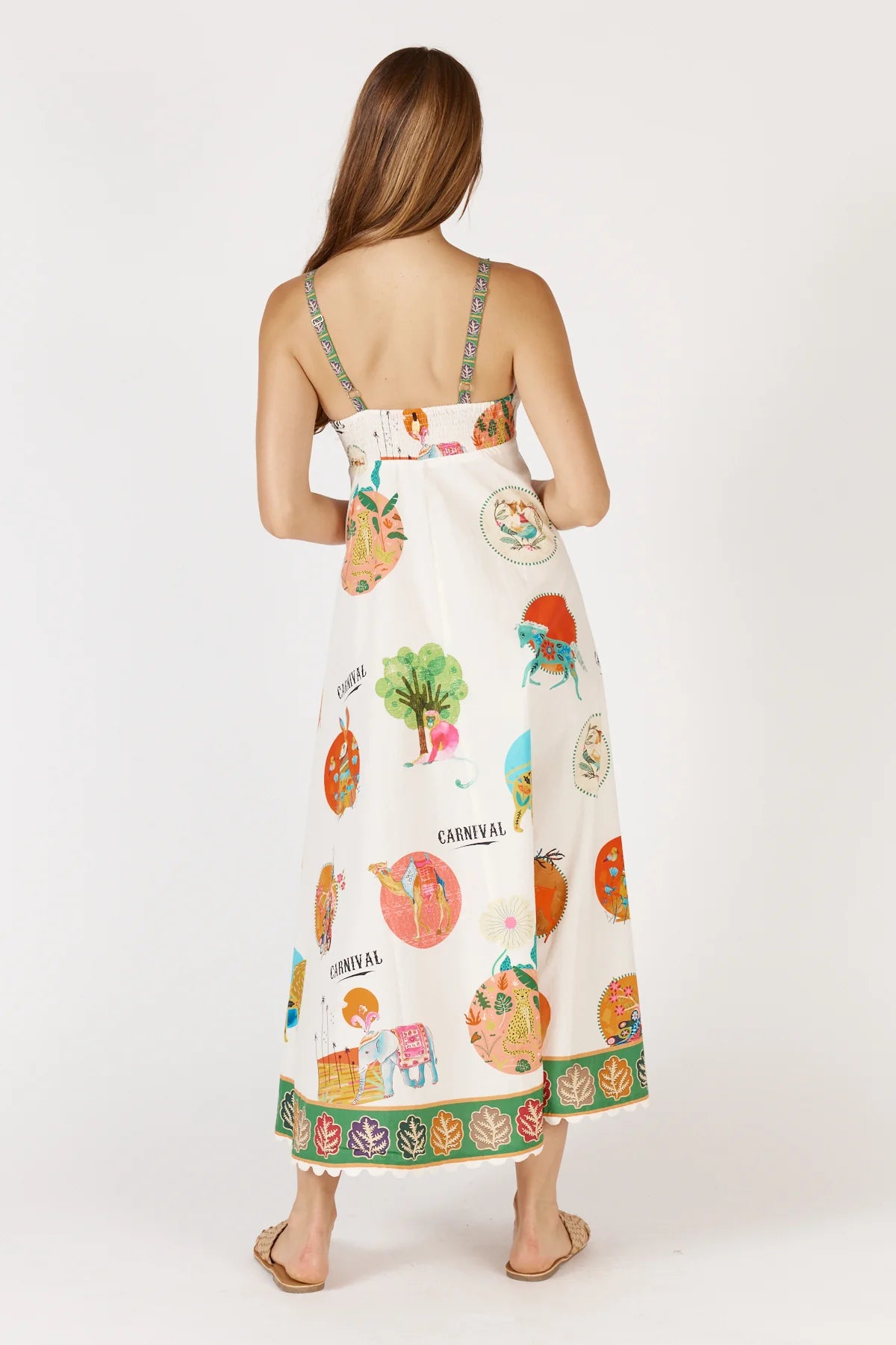 Down Under Sundress in white featuring a colorful carnival print, straight neckline, adjustable straps, and scalloped hem with leaf border detailing.
