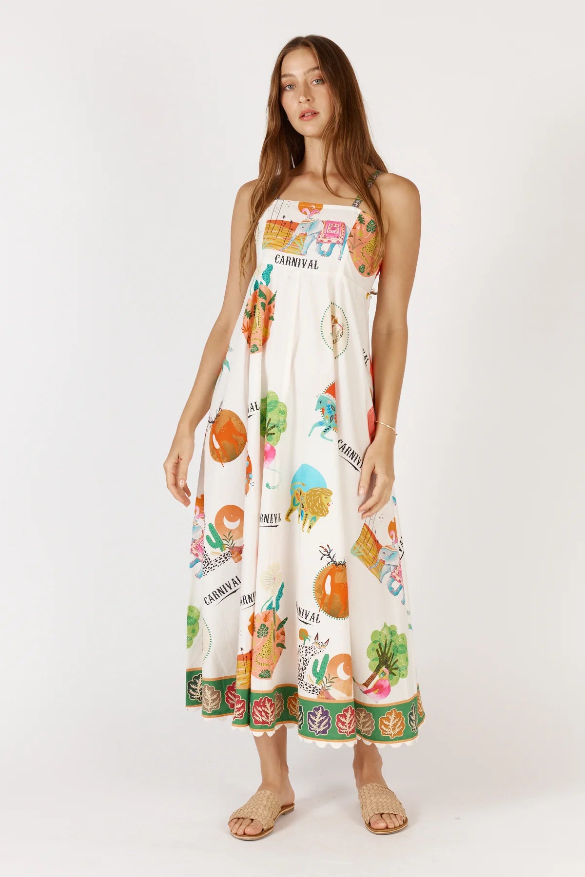 Down Under Sundress in white featuring a colorful carnival print, straight neckline, adjustable straps, and scalloped hem with leaf border detailing.
