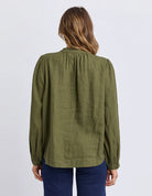 The Eleanor Shirt featuring a high neckline, button-through front, delicate chest embroidery, and softly gathered long sleeves in a relaxed, feminine silhouette.